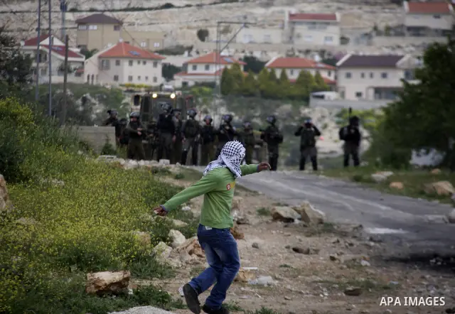 A Palestinian protester throws stones at Israeli soldiers during a demonstration to mark the anniversary of Land Day in the village Kafr Qaddum, close to the northern town of Nablus in the occupied Israeli West bank on M...