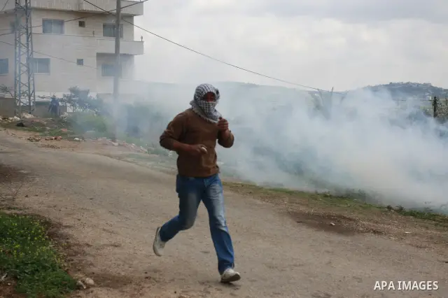 A Palestinian protester run for cover from tear gas canisters fired by Israeli soldiers during a demonstration to mark the anniversary of Land Day in the village Kafr Qaddum, close to the northern town of Nablus in the o...
