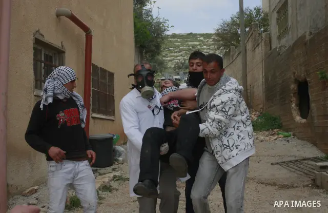 Palestinians carry an injured protester during clashes between Palestinian protesters and Israeli soldiers following a demonstration to mark the anniversary of Land Day in the village Kafr Qaddum, close to the northern t...
