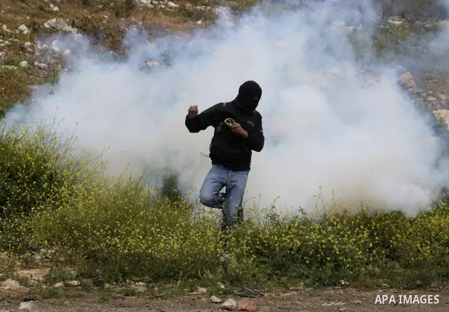 A Palestinian protester run for cover from tear gas canisters fired by Israeli soldiers during a demonstration to mark the anniversary of Land Day in the village Kafr Qaddum, close to the northern town of Nablus in the o...
