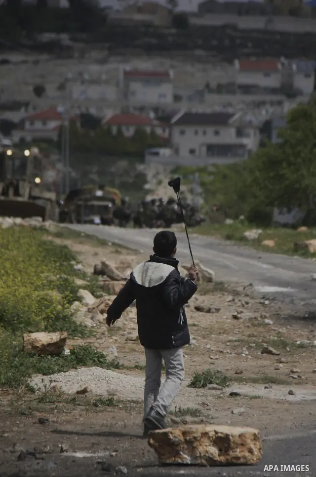 A Palestinian protester throws stones at Israeli soldiers during a demonstration to mark the anniversary of Land Day in the village Kafr Qaddum, close to the northern town of Nablus in the occupied Israeli West bank on M...