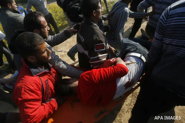 Palestinians carry a wounded protester during clashes with Israeli security forces at a protest near the border between Israel and southern Gaza Strip March 30, 2012. Israeli security forces fired rubber bullets, tear ga...