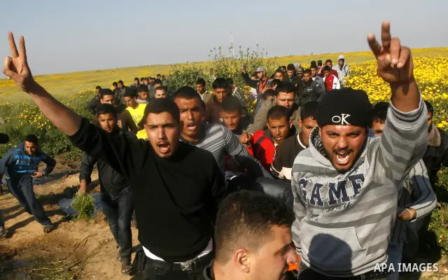 Palestinians carry a wounded protester during clashes with Israeli security forces at a protest near the border between Israel and southern Gaza Strip March 30, 2012. Israeli security forces fired rubber bullets, tear ga...