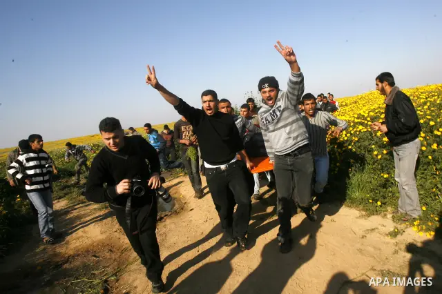 Palestinians carry a wounded protester during clashes with Israeli security forces at a protest near the border between Israel and southern Gaza Strip March 30, 2012. Israeli security forces fired rubber bullets, tear ga...