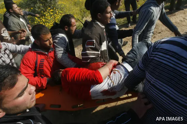 Palestinians carry a wounded protester during clashes with Israeli security forces at a protest near the border between Israel and southern Gaza Strip March 30, 2012. Israeli security forces fired rubber bullets, tear ga...