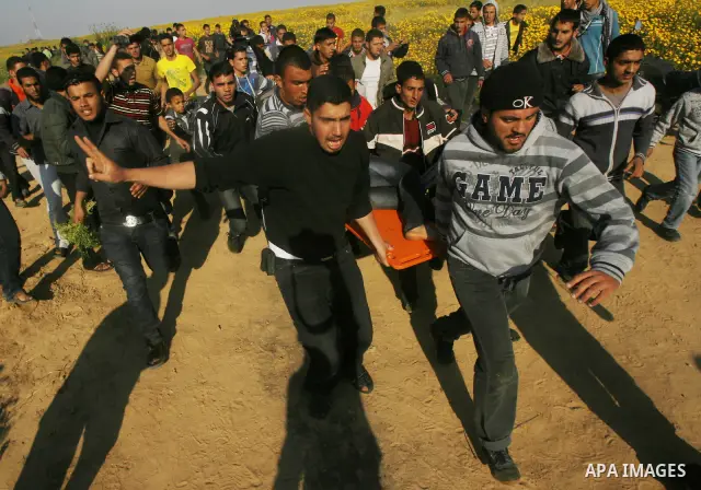 Palestinians carry a wounded protester during clashes with Israeli security forces at a protest near the border between Israel and southern Gaza Strip March 30, 2012. Israeli security forces fired rubber bullets, tear ga...
