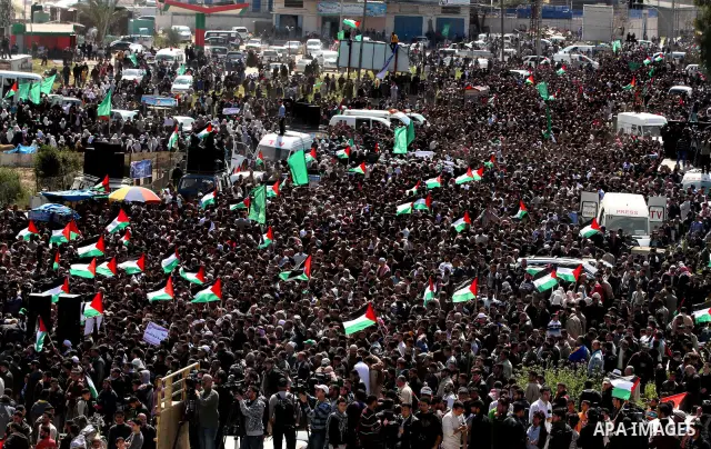 Palestinian protesters hold up their national flag as they protest close to the border between Israel and the northern Gaza Strip, during Land Day demonstrations in Beit Hanun, on March 30, 2012. Rallies were held across...