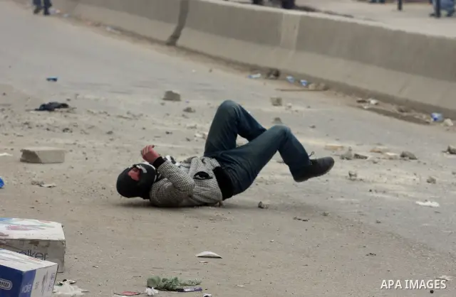 A Palestinian protester lies on the ground after being allegedly hit by a rubber bullet during clashes with Israeli soldiers as Palestinians gathered to mark the anniversary of Land Day in Qalandia which lies between Jer...