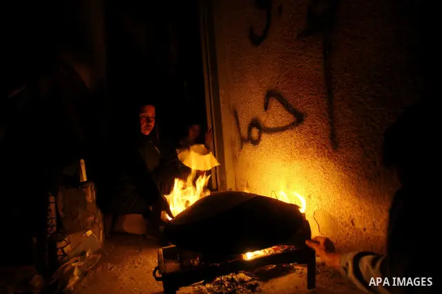 Palestinians prepare freshly baked pita bread at a traditional bakery using a wood burning stove in the Rafah refugee camp in the southern Gaza Strip on March 31, 2012. Gaza is experiencing a major electricity crisis bec...