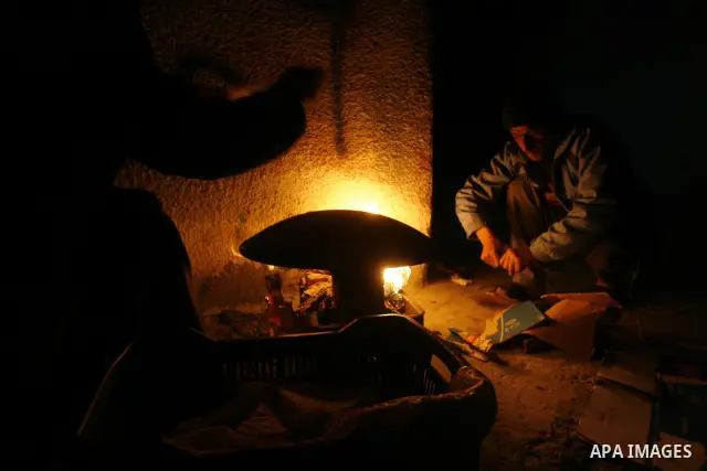 Palestinians prepare freshly baked pita bread at a traditional bakery using a wood burning stove in the Rafah refugee camp in the southern Gaza Strip on March 31, 2012. Gaza is experiencing a major electricity crisis bec...