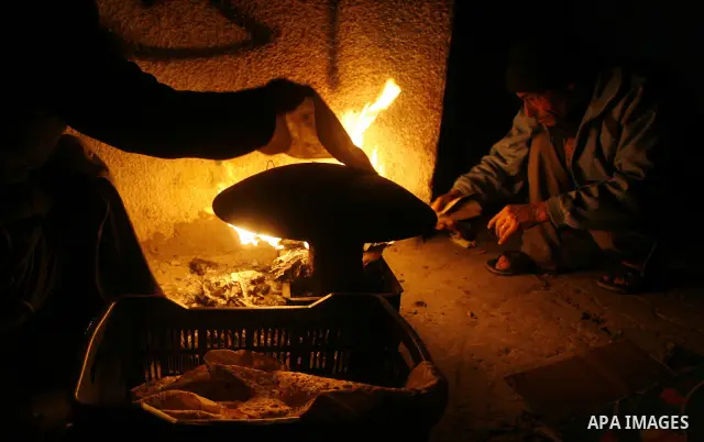Palestinians prepare freshly baked pita bread at a traditional bakery using a wood burning stove in the Rafah refugee camp in the southern Gaza Strip on March 31, 2012. Gaza is experiencing a major electricity crisis bec...