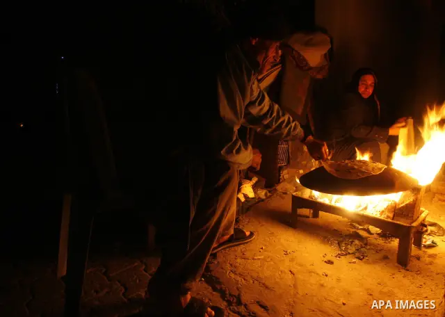 Palestinians prepare freshly baked pita bread at a traditional bakery using a wood burning stove in the Rafah refugee camp in the southern Gaza Strip on March 31, 2012. Gaza is experiencing a major electricity crisis bec...