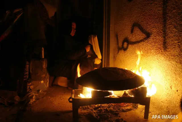 Palestinians prepare freshly baked pita bread at a traditional bakery using a wood burning stove in the Rafah refugee camp in the southern Gaza Strip on March 31, 2012. Gaza is experiencing a major electricity crisis bec...