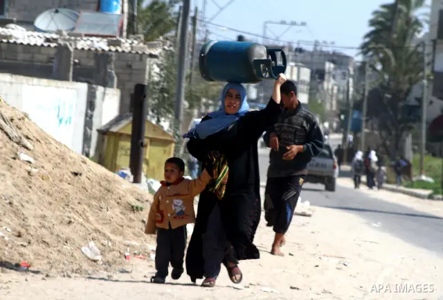 A Palestinian woman carries a cooking gas canister in Deir al-Balah in the central Gaza Strip April 1, 2012. Palestinians in the Gaza Strip are experiencing a shortage of gas and fuel. Photo by Ashraf Amra