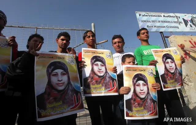 Palestinians hold posters of Hanaa Shalabi, a prisoner who spent 43 days on hunger strike, as they wait to greet her near the Erez border crossing between Israel and the northern Gaza Strip on April 1, 2012. Shalabi, who...