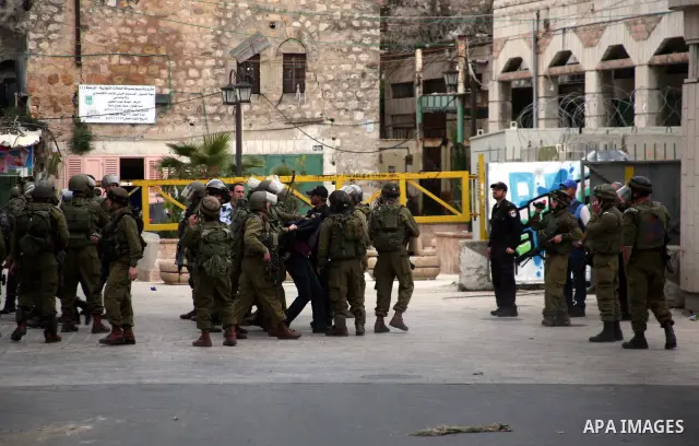 Israeli policemen and soldiers detain Palestinian protesters and foreign activists on April 01, 2012, after they took refuge in an abandoned house and fly a Palestinian flag on the rooftop of the building near the Beit R...
