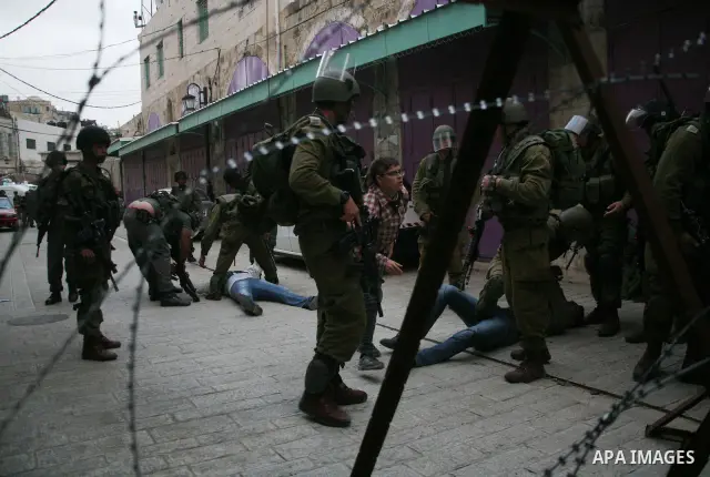 Israeli policemen and soldiers detain Palestinian protesters and foreign activists on April 01, 2012, after they took refuge in an abandoned house and fly a Palestinian flag on the rooftop of the building near the Beit R...