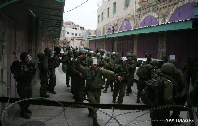Israeli policemen and soldiers detain Palestinian protesters and foreign activists on April 01, 2012, after they took refuge in an abandoned house and fly a Palestinian flag on the rooftop of the building near the Beit R...