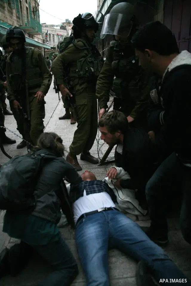 Israeli policemen and soldiers detain Palestinian protesters and foreign activists on April 01, 2012, after they took refuge in an abandoned house and fly a Palestinian flag on the rooftop of the building near the Beit R...