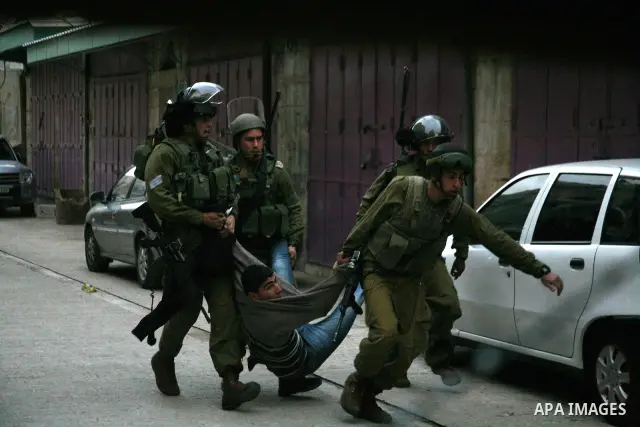 Israeli policemen and soldiers detain Palestinian protesters and foreign activists on April 01, 2012, after they took refuge in an abandoned house and fly a Palestinian flag on the rooftop of the building near the Beit R...
