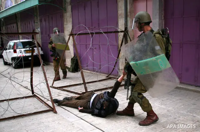 Israeli policemen and soldiers detain Palestinian protesters and foreign activists on April 01, 2012, after they took refuge in an abandoned house and fly a Palestinian flag on the rooftop of the building near the Beit R...