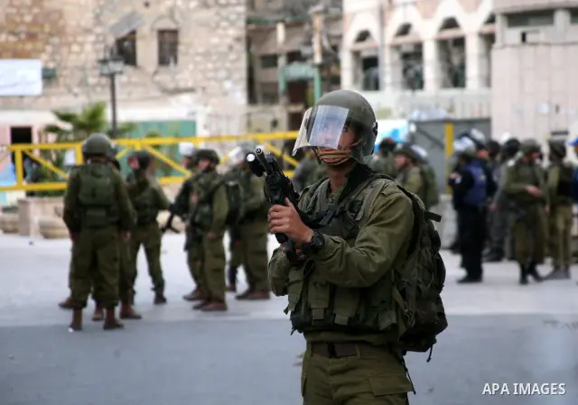 Israeli policemen and soldiers detain Palestinian protesters and foreign activists on April 01, 2012, after they took refuge in an abandoned house and fly a Palestinian flag on the rooftop of the building near the Beit R...