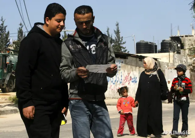 Palestinians read sheets which were thrown by Israeli aeroplane warning the Palestinians from reaching the no-go zone on the border with Israel,in the Rafah on the southern Gaza Strip on April 2,2012. Photo by Eyad Al Ba...