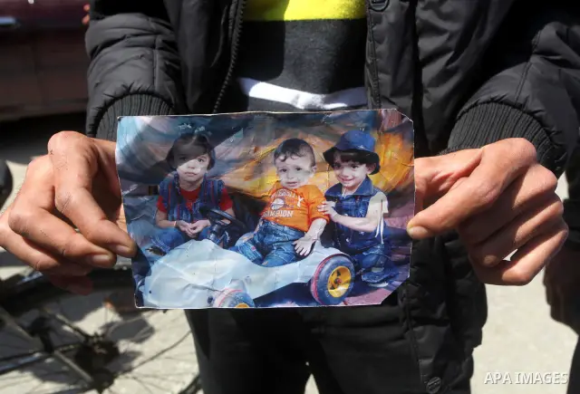 Palestinian mourners hold the pictures of three children (from L-R: Nadine, Sabri and Farah Bashir) who were killed the previous day in a domestic fire during their funeral procession in Deir al-Balah in the central Gaza...