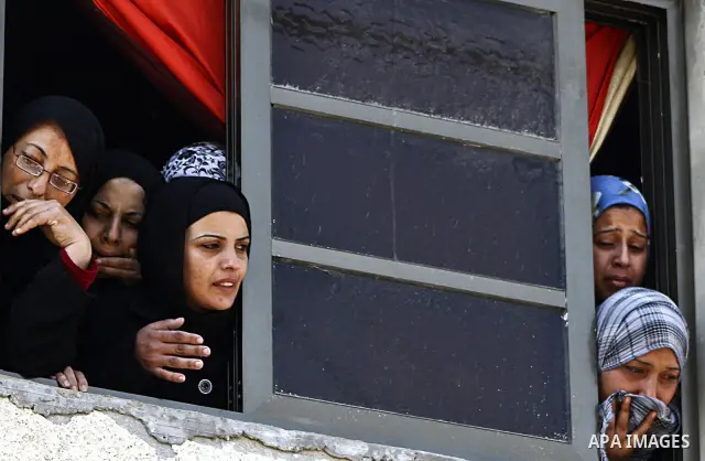 Palestinian relatives cry as mourners carry the bodies of three children who died in a domestic fire during their funeral during their funeral procession in Deir al-Balah in the central Gaza Strip on April 02, 2012. The...