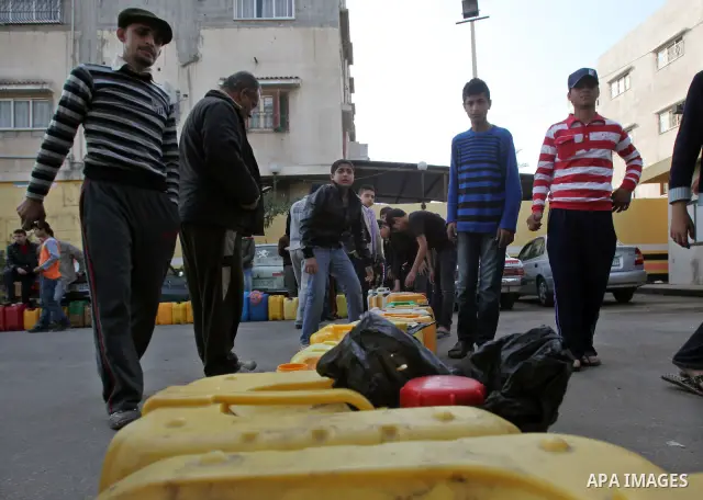 Palestinians wait in a queue to fill containers with fuel at a petrol station in Gaza City on April 2, 2012. The International Committee of the Red Cross (ICRC) began transferring emergency supplies of fuel to the Gaza S...