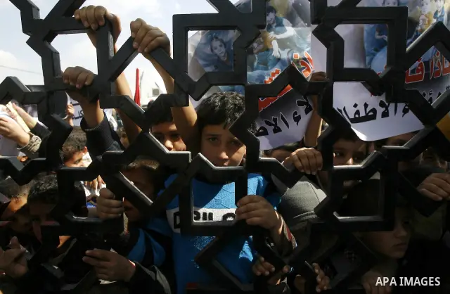 Palestinian boys hold a poster of three children who were killed in a fire caused by a candle being used due to lack of electricity during a protest against the electricity crisis near the southern Gaza Strip's Rafah bor...