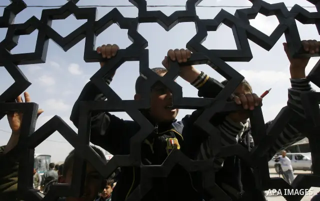 Palestinian boys climb a fence during a rally near Rafah border crossing between Egypt and the southern Gaza Strip, calling on the Egyptian authorities to supply the Gaza Strip with fuel and electricity April 3, 2012. Th...