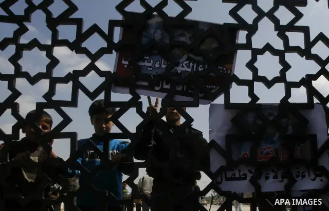 Palestinian boys hold a poster of three children who were killed in a fire caused by a candle being used due to lack of electricity during a protest against the electricity crisis near the southern Gaza Strip's Rafah bor...