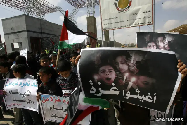 Palestinian boys hold a poster of children reading "Rescue Gaza" as another flashes the victory sign near the southern Gaza Strip's Rafah border crossing with Egypt on April 3, 2012 during a protest against the electrici...