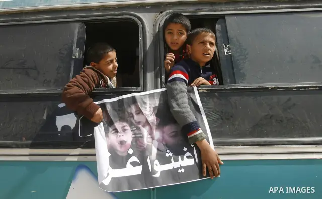 Palestinian boys hold a poster of children reading "Rescue Gaza" as another flashes the victory sign near the southern Gaza Strip's Rafah border crossing with Egypt on April 3, 2012 during a protest against the electrici...