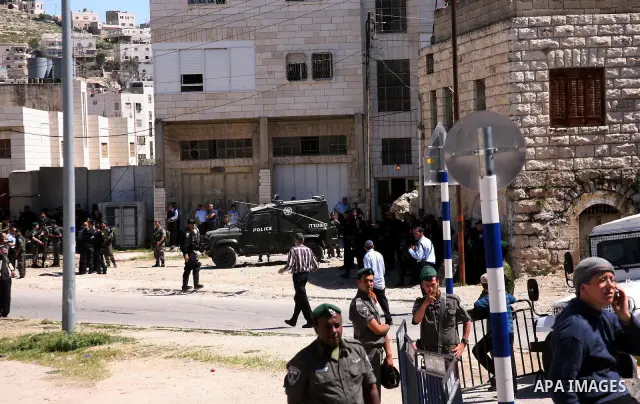 Jewish settlers stands near Israeli border policemen as they prevent her from reaching a building, occupied by Jewish settlers, in the West Bank city of Hebron April 4, 2012. Israeli police evicted Jewish settlers on Wed...