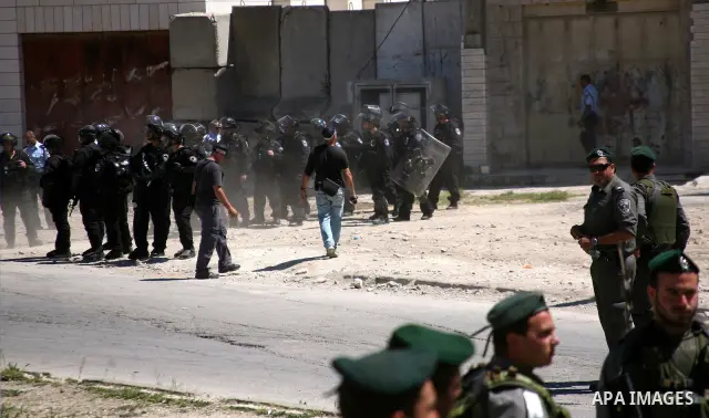 Jewish settlers stands near Israeli border policemen as they prevent her from reaching a building, occupied by Jewish settlers, in the West Bank city of Hebron April 4, 2012. Israeli police evicted Jewish settlers on Wed...