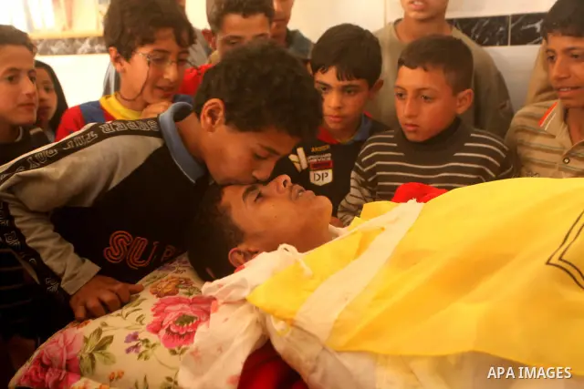 Palestinian children gather around the body of Palestinian youth Hashem Saed, 17-years-old, during his funeral in Gaza City on April 4, 2012, after he was shot overnight close along the border fence between the Gaza Stri...