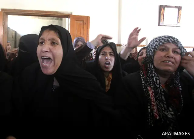 Palestinian women grieve as they watch the body of Palestinian youth Hashem Saed, 17-years-old, leave his home during his funeral in Gaza City on April 4, 2012, after he was shot overnight close along the border fence be...