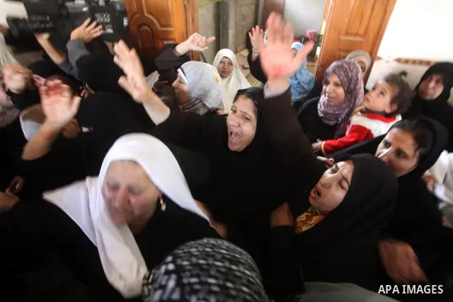 Palestinian women grieve as they watch the body of Palestinian youth Hashem Saed, 17-years-old, leave his home during his funeral in Gaza City on April 4, 2012, after he was shot overnight close along the border fence be...