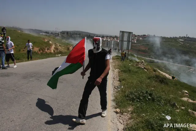 Palestinian protesters run for cover from teargas fired by Israeli soldiers in the West Bank village of Nabi Saleh, near Ramallah, on April 6, 2012 during a protest against Palestinian land confiscation to expand the Jew...