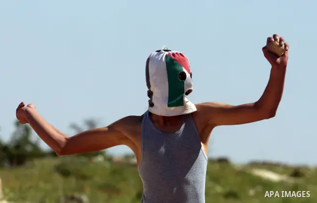 A Palestinian man throws stones towards the Israeli soldiers in the West Bank village of Nabi Saleh, near Ramallah, on April 6, 2012 during a protest against Palestinian land confiscation to expand the Jewish Hallamish s...