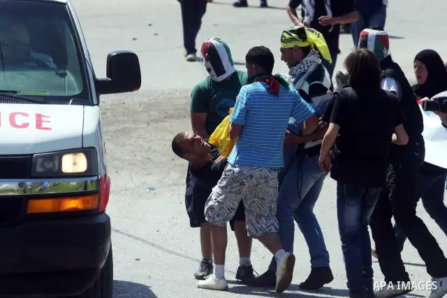 Palestinian demonstrators hold a man injured by a teargas canister during a protest against the expansion of the nearby Jewish settlement of Halamish in the West Bank village of Nabi Saleh near Ramallah, Friday, April 6,...
