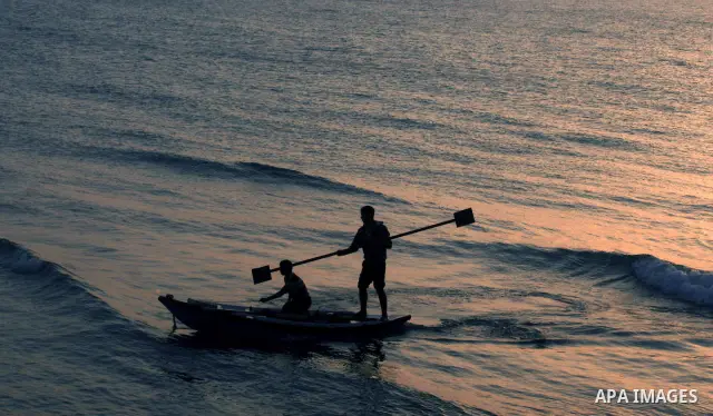 A Palestinian fisherman is seen silhouetted on his boat on the Mediterranean sea after sunset in the West of Gaza city on 06 April 2012. Photo by Emad Nassar