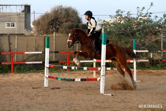 A Palestinian girl rides a horse during a championship at Gaza Horse Club in Gaza Strip, 06 April 2012. The clubs is home to some 54 horses and open for the training of male and female children aged between 12 to 23 year...