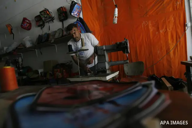 A Palestinian tailor sews of the school bags in his shop in the southern Gaza Strip refugee camp of Rafah, in Apr. 08, 2012. Photo by Eyad Al Baba