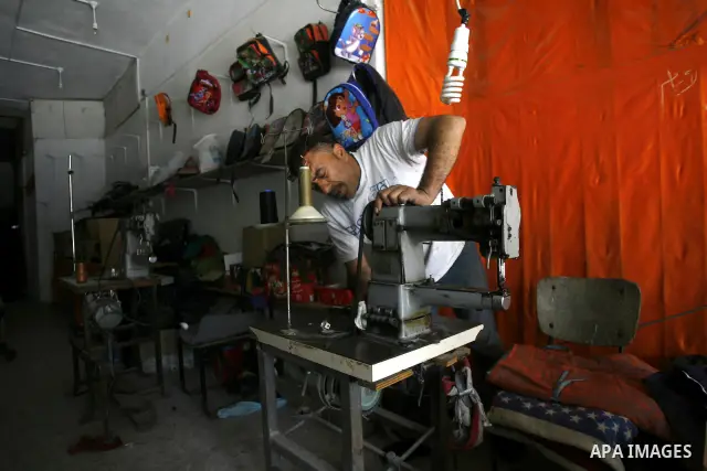 A Palestinian tailor sews of the school bags in his shop in the southern Gaza Strip refugee camp of Rafah, in Apr. 08, 2012. Photo by Eyad Al Baba