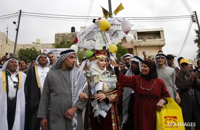 The Palestinian bride and groom Mhaha Salam (R) and Thayer Qasem (L), walk down the street on their wedding day on April 12, 2012 after they traveled from the refugee camp of al-Yarmuk in Syria, to get married in the Wes...