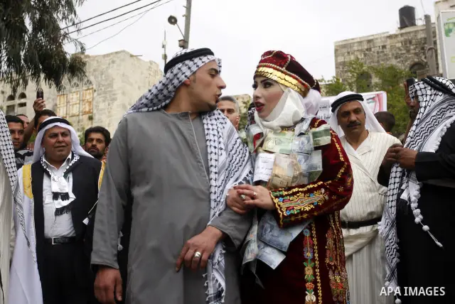 The Palestinian bride and groom Mhaha Salam (R) and Thayer Qasem (L), walk down the street on their wedding day on April 12, 2012 after they traveled from the refugee camp of al-Yarmuk in Syria, to get married in the Wes...