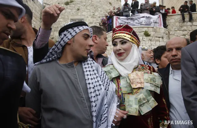 The Palestinian bride and groom Mhaha Salam (R) and Thayer Qasem (L), walk down the street on their wedding day on April 12, 2012 after they traveled from the refugee camp of al-Yarmuk in Syria, to get married in the Wes...